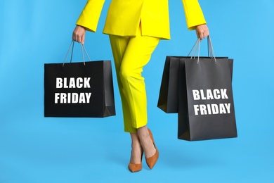 Woman with shopping bags on light blue background, closeup. Black Friday