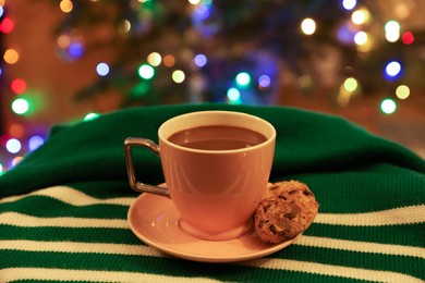 Cup of delicious hot cocoa and cookie on colorful cloth