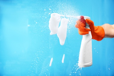 Photo of Woman cleaning glass against color background