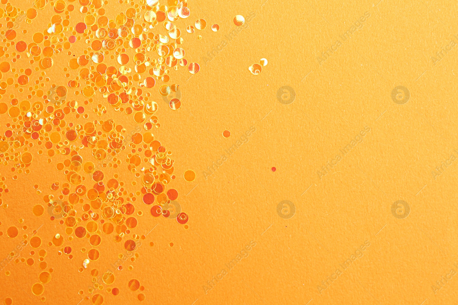 Photo of Shiny bright glitter on orange background, flat lay. Space for text