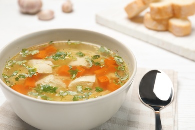 Photo of Bowl with fresh homemade chicken soup on table, closeup