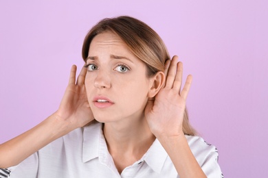 Young woman with hearing problem on color background