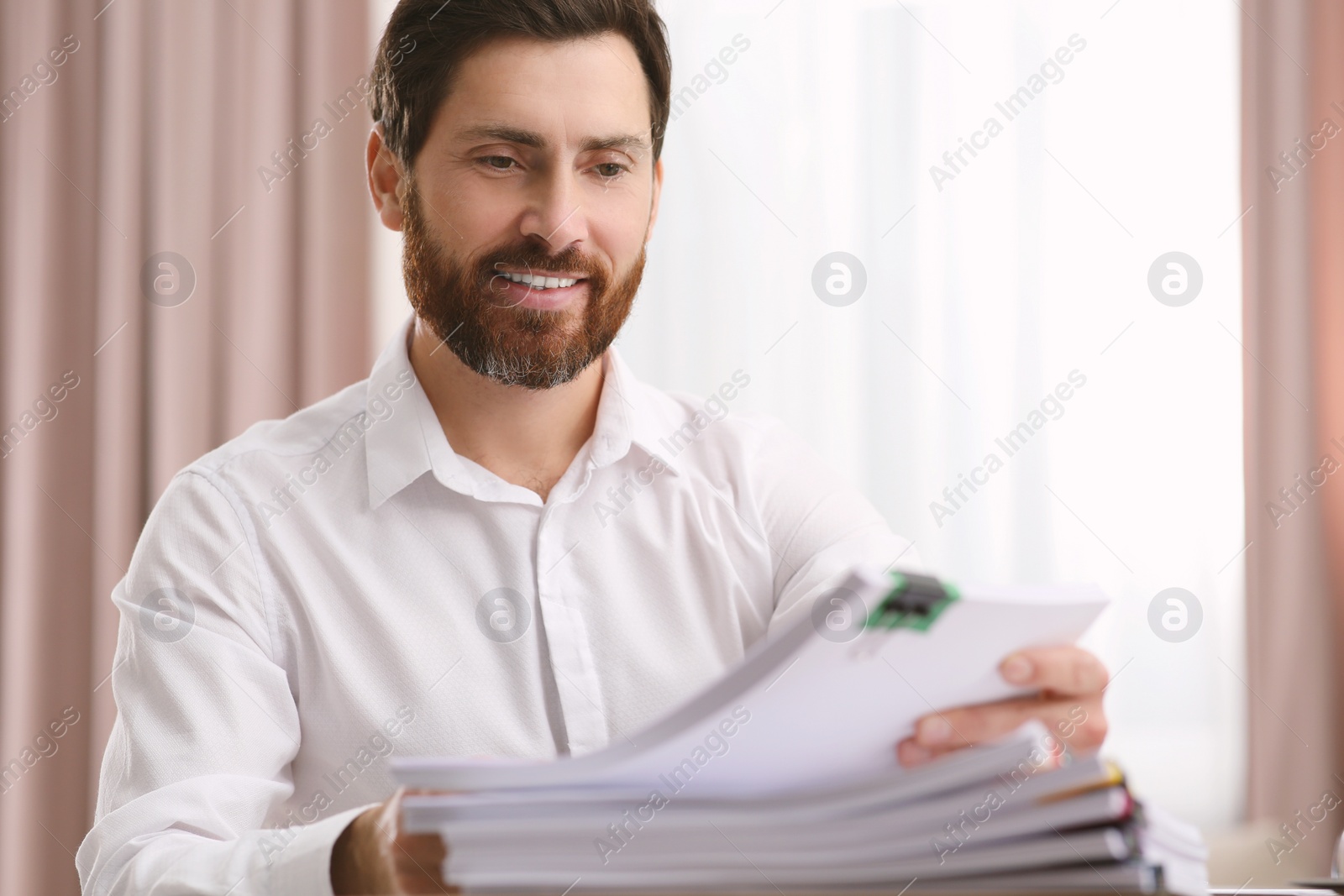 Photo of Happy businessman working with documents in modern office