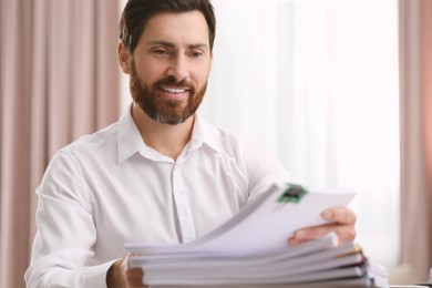 Photo of Happy businessman working with documents in modern office