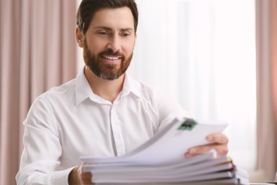 Happy businessman working with documents in modern office