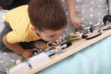 Little children playing with busy board on bed