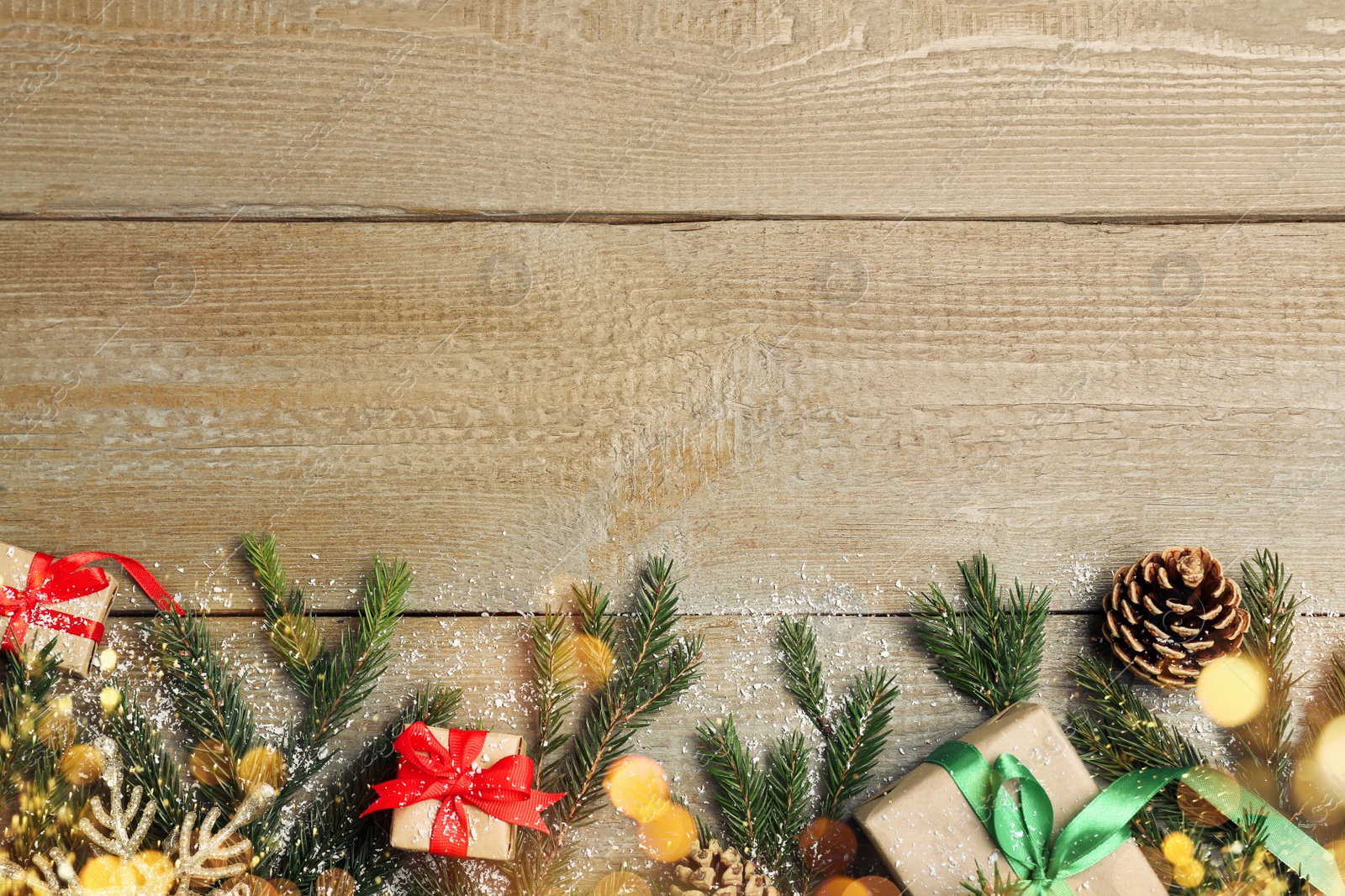 Photo of Christmas greeting card with space for text. Flat lay composition of fir tree branches and festive decor on wooden background