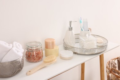 Different bath accessories and personal care products on table near white wall