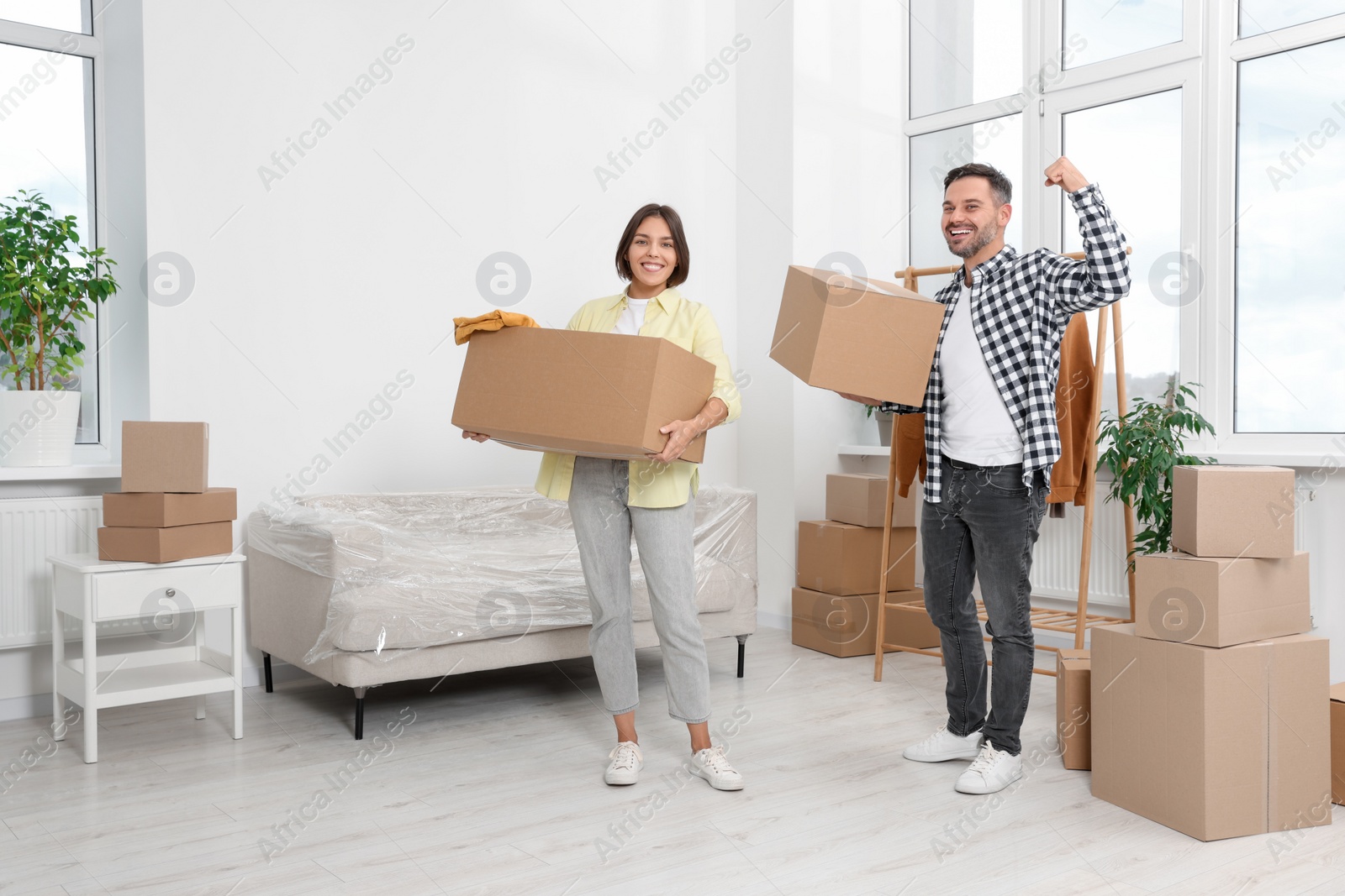 Photo of Happy couple with moving boxes in new apartment