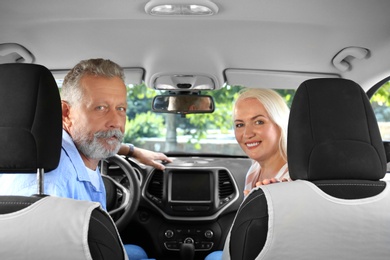 Happy senior couple sitting together in car