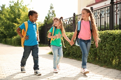 Photo of Cute little children with backpacks going to school