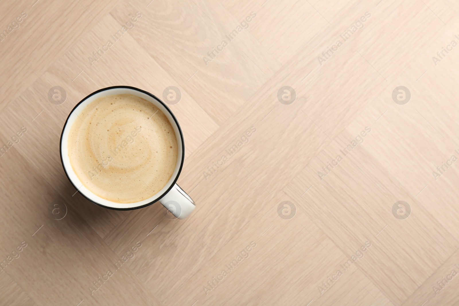 Photo of Tasty cappuccino in cup on light wooden table, top view. Space for text