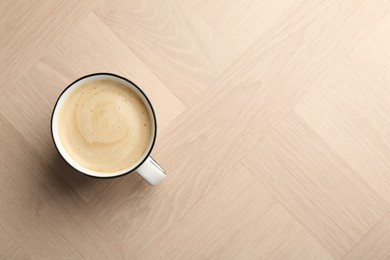 Photo of Tasty cappuccino in cup on light wooden table, top view. Space for text