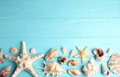 Photo of Flat lay composition with beautiful starfishes and sea shells on blue wooden table, space for text