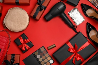 Photo of Gift boxes, cosmetics, hairdryer, shoes and women's accessories on red background, flat lay. Space for text