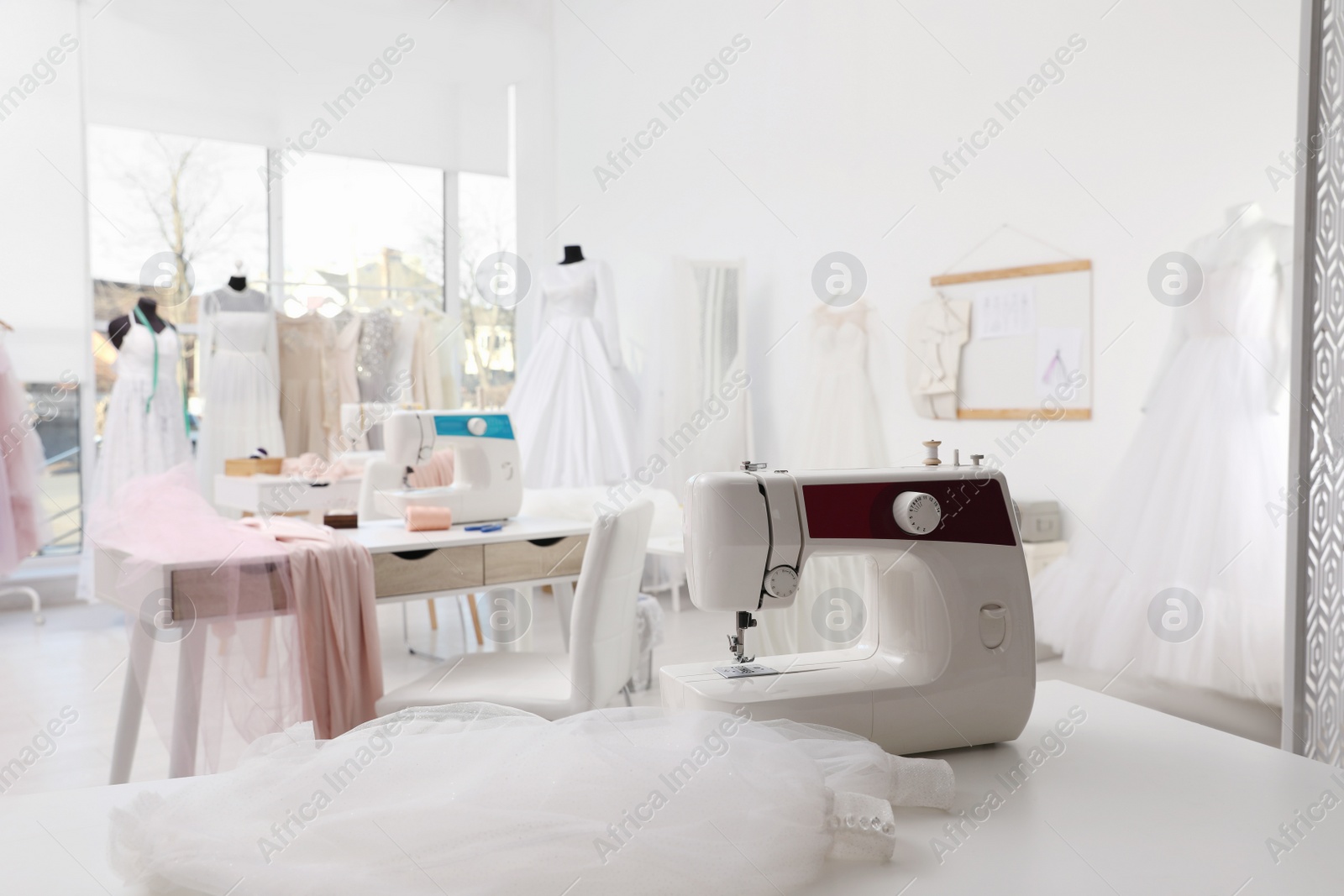 Photo of Sewing machine and fabric on table in dressmaking workshop