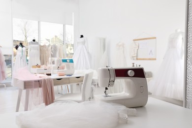 Photo of Sewing machine and fabric on table in dressmaking workshop