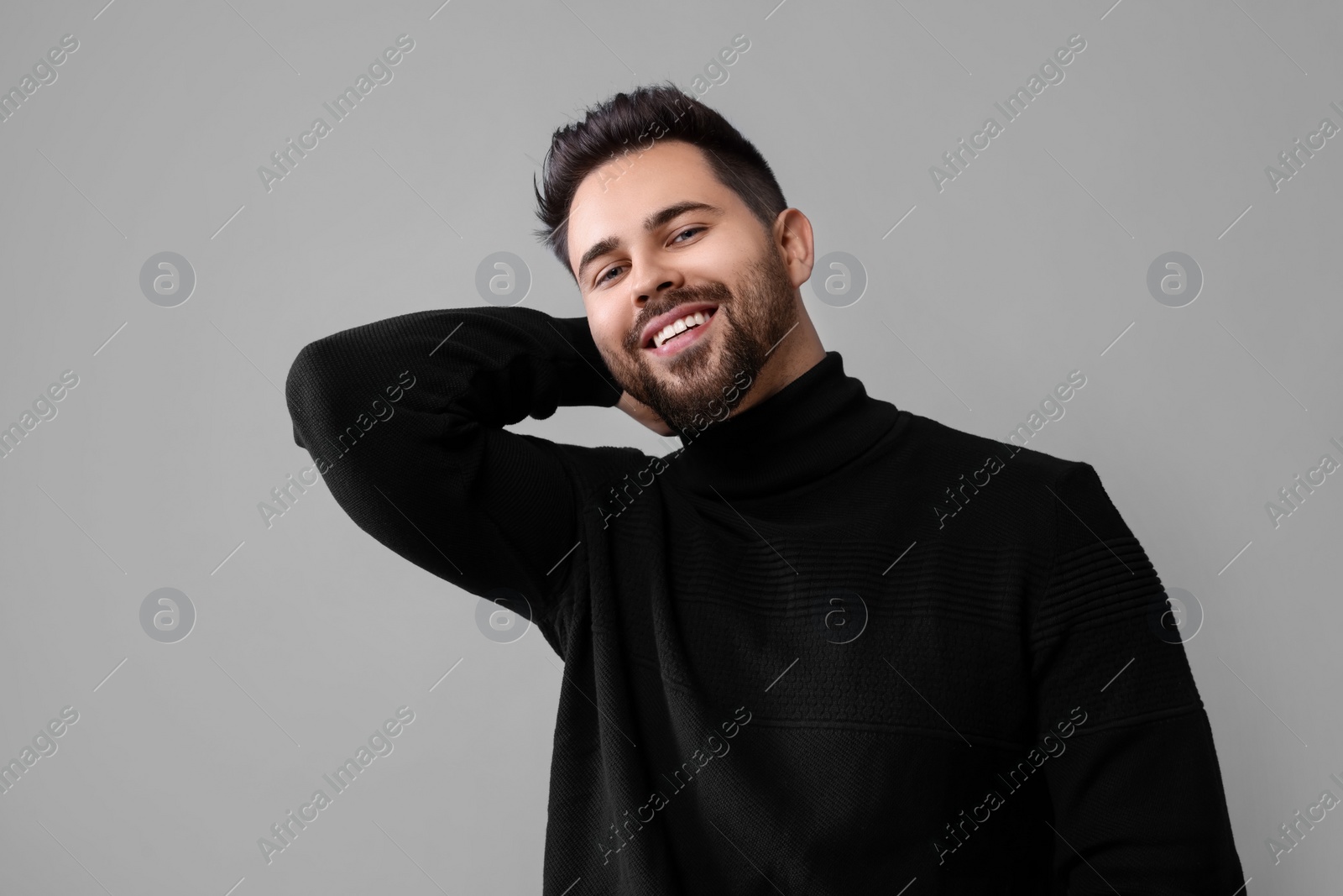 Photo of Happy man in stylish black sweater on grey background