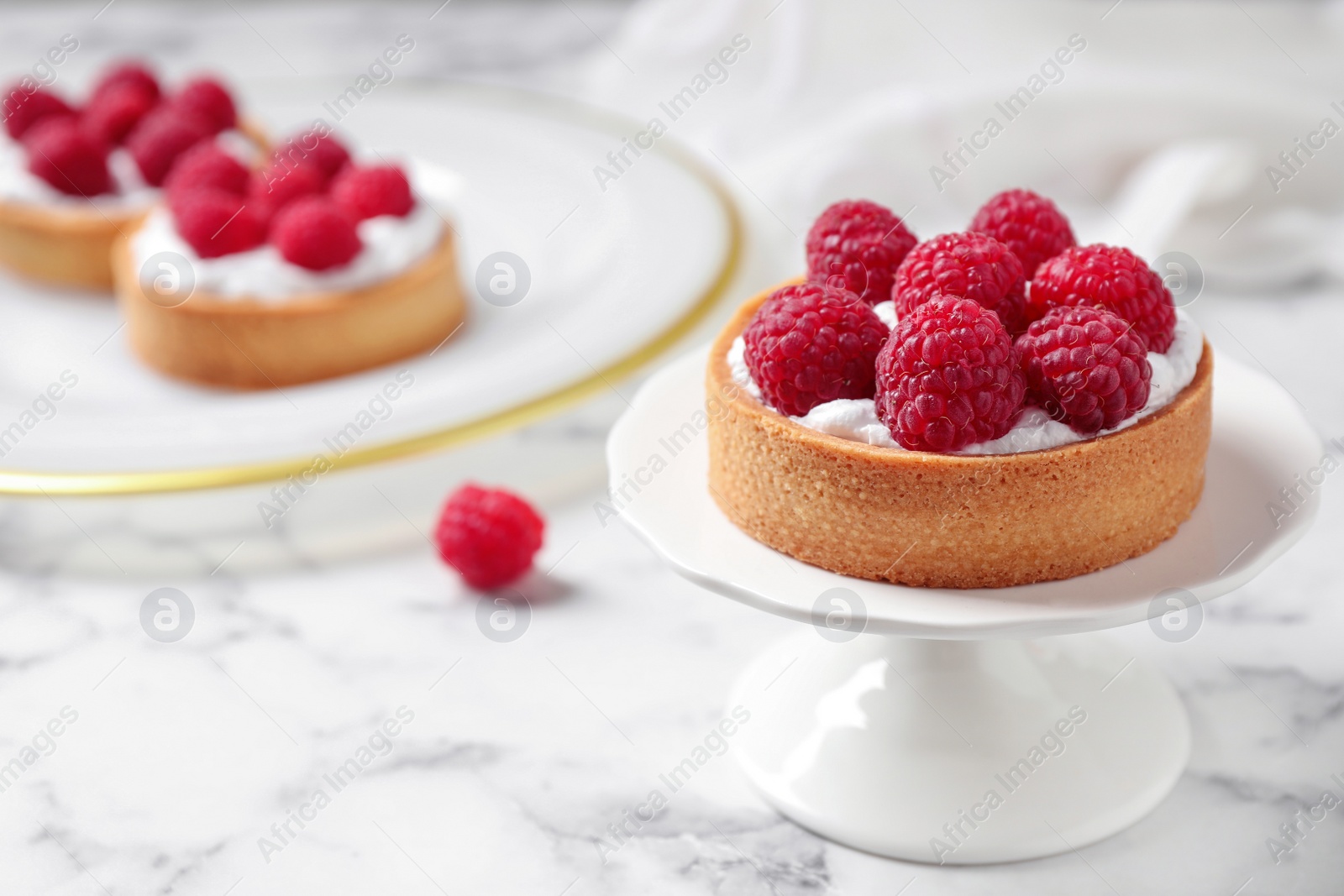 Photo of Cake stand with raspberry tart on marble table, space for text. Delicious pastries