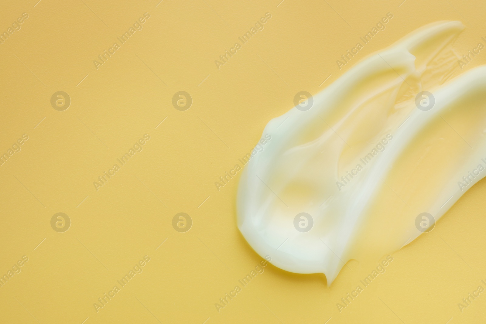 Photo of Sample of face cream on yellow background, top view. Space for text