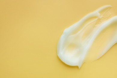 Sample of face cream on yellow background, top view. Space for text