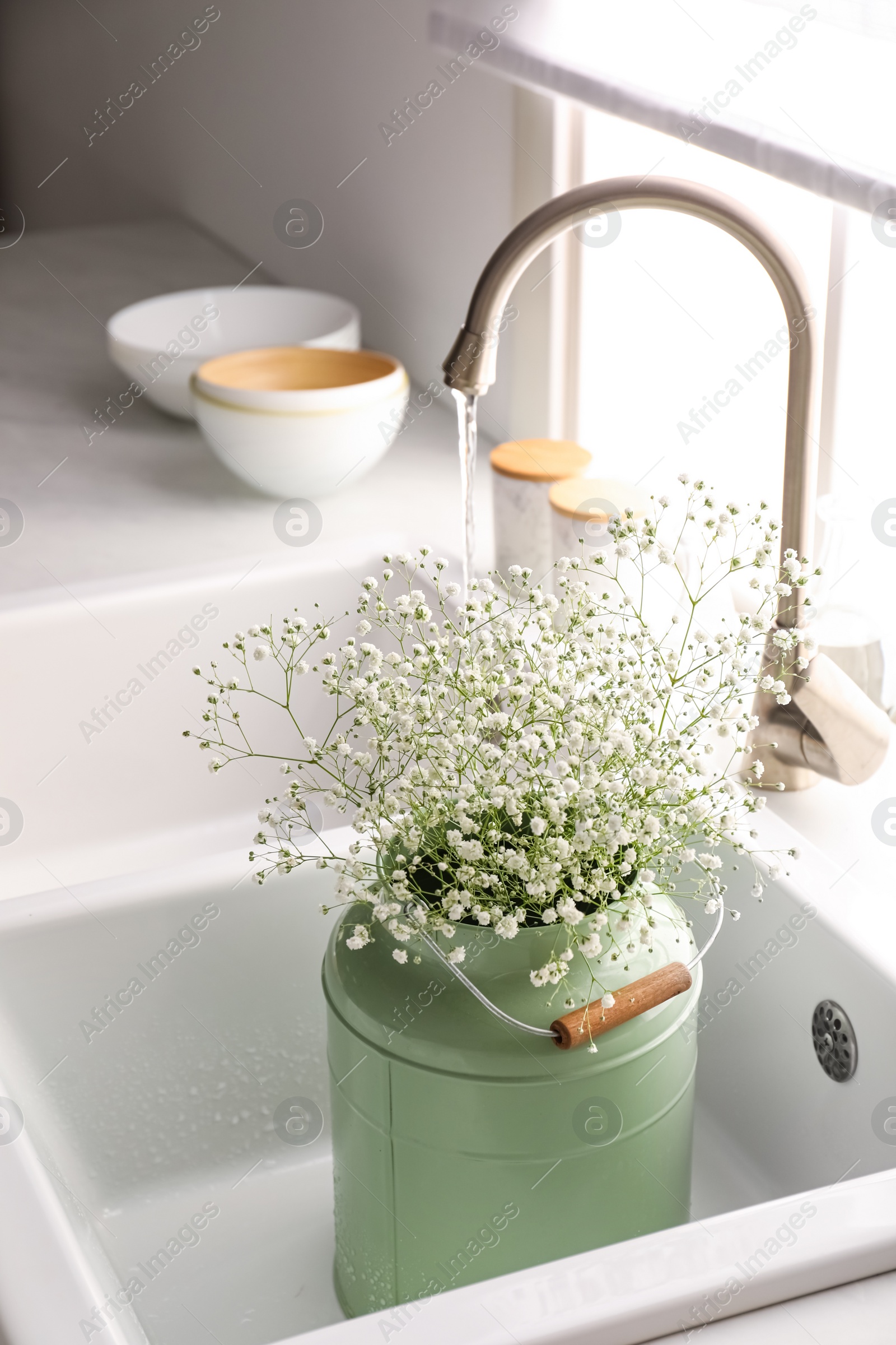 Photo of Bouquet of gypsophila flowers in sink. Kitchen interior design