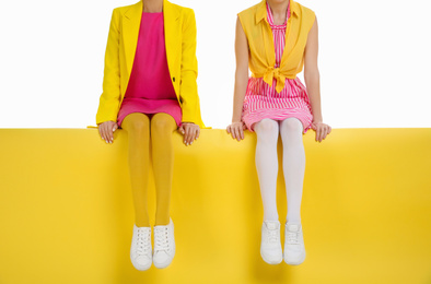 Women wearing bright tights sitting on color background, closeup