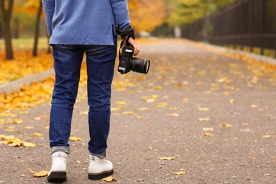 Photographer with professional camera outdoors on autumn day, closeup. Space for text