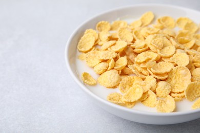 Photo of Breakfast cereal. Corn flakes and milk in bowl on light grey table, closeup. Space for text