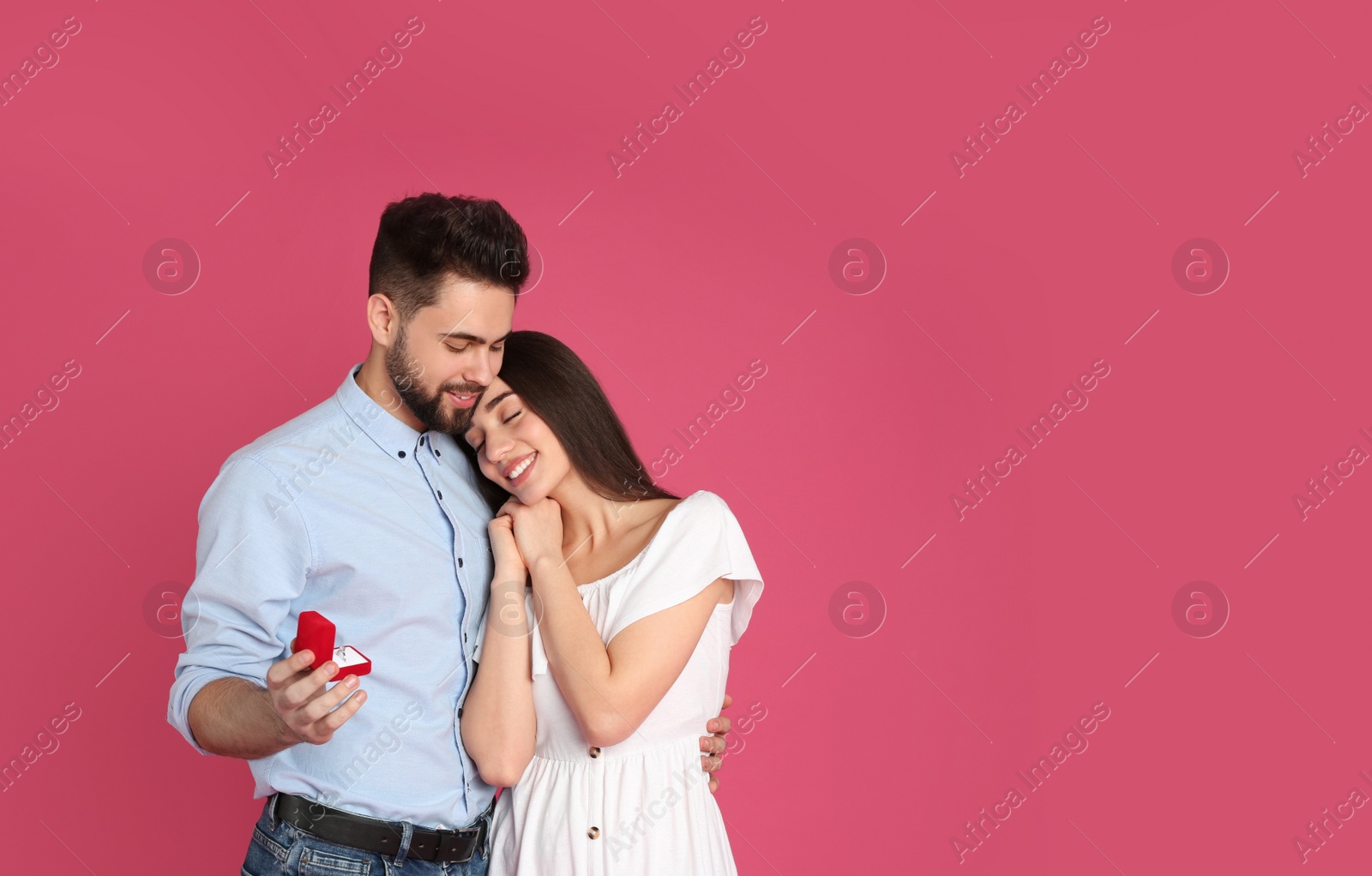 Photo of Man with engagement ring making marriage proposal to girlfriend on crimson background