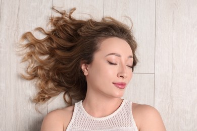 Photo of Portrait of beautiful woman with closed eyes on wooden floor, top view