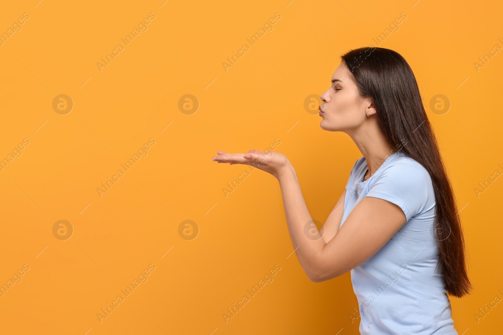Photo of Beautiful young woman blowing kiss on yellow background. Space for text