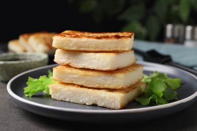 Photo of Delicious turnip cake with lettuce salad served on grey table, closeup