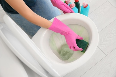 Woman cleaning toilet bowl in bathroom