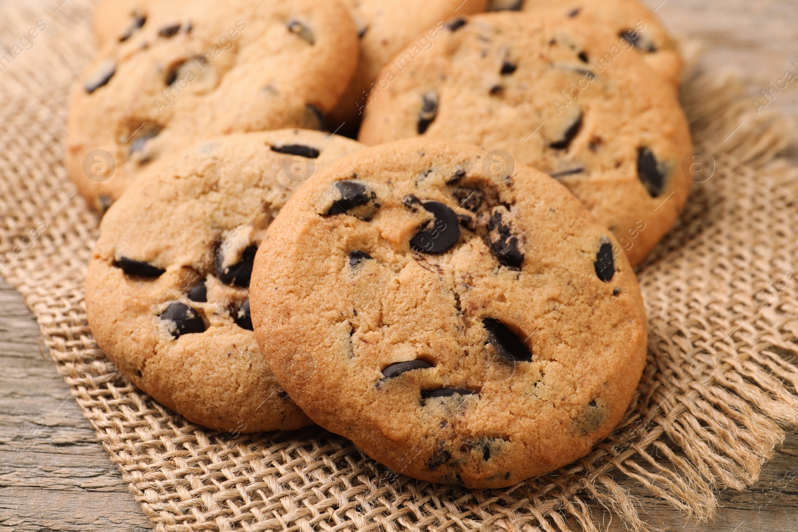 Photo of Delicious chocolate chip cookies on burlap fabric, closeup