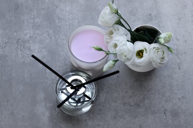 Photo of Reed diffuser, scented candle and eustoma flowers on gray marble table, flat lay