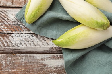 Photo of Fresh raw Belgian endives (chicory) on wooden table, top. Space for text