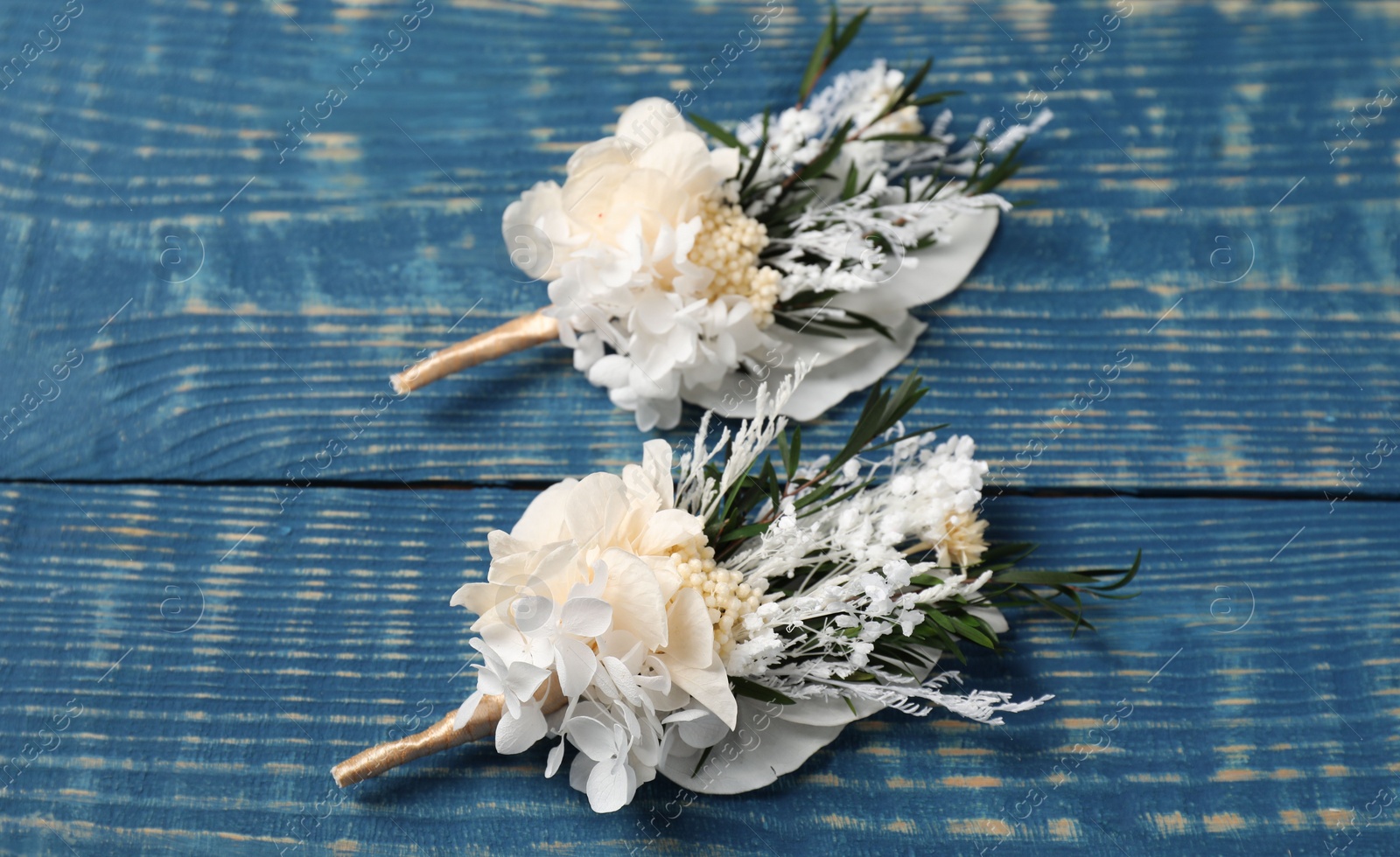 Photo of Stylish white boutonnieres on blue wooden table