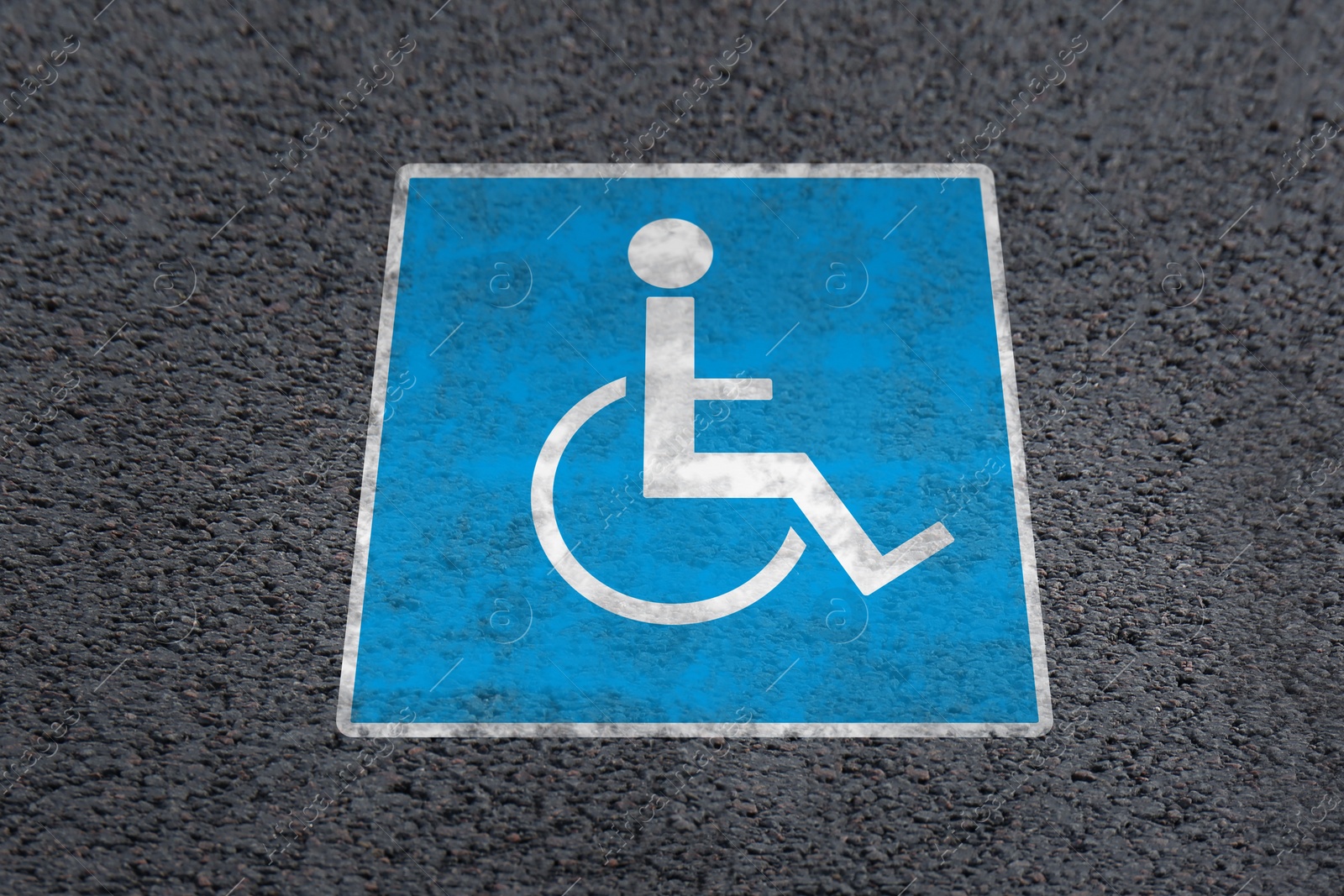 Image of Wheelchair symbol on asphalt road, above view. Disabled parking permit