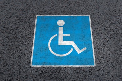 Image of Wheelchair symbol on asphalt road, above view. Disabled parking permit
