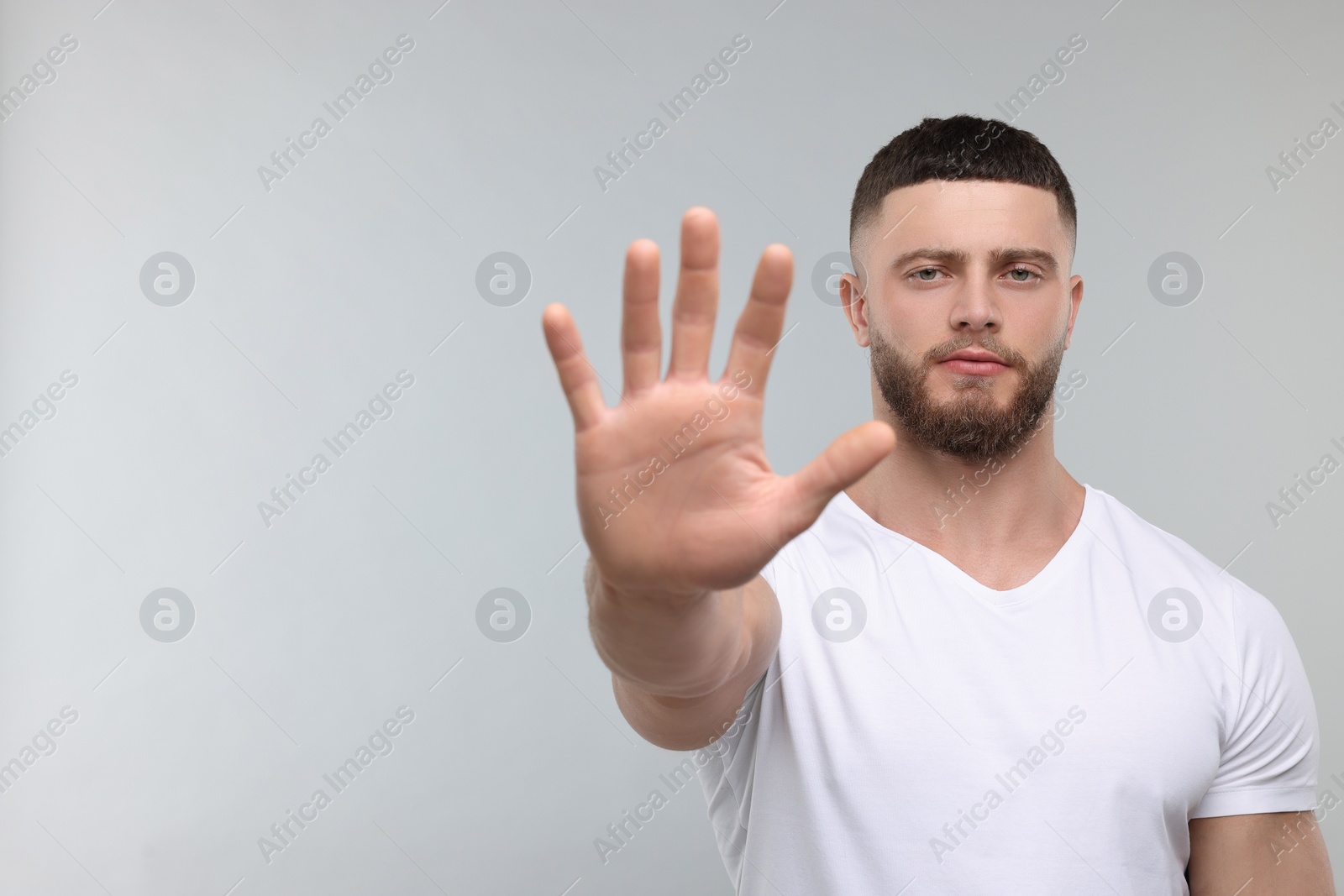 Photo of Man showing stop gesture on light grey background, space for text