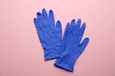 Photo of Pair of medical gloves on pink background, flat lay