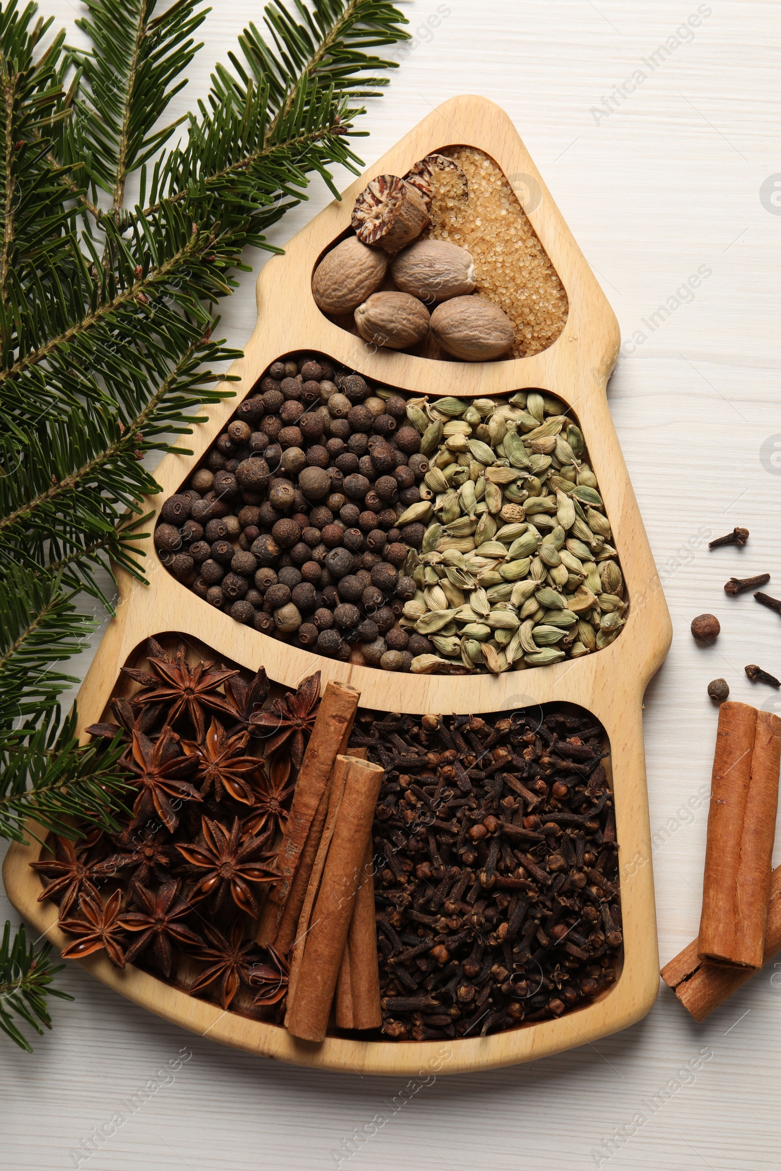 Photo of Different spices, nuts and fir branches on white wooden table, flat lay