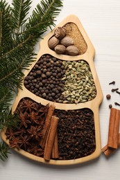 Different spices, nuts and fir branches on white wooden table, flat lay