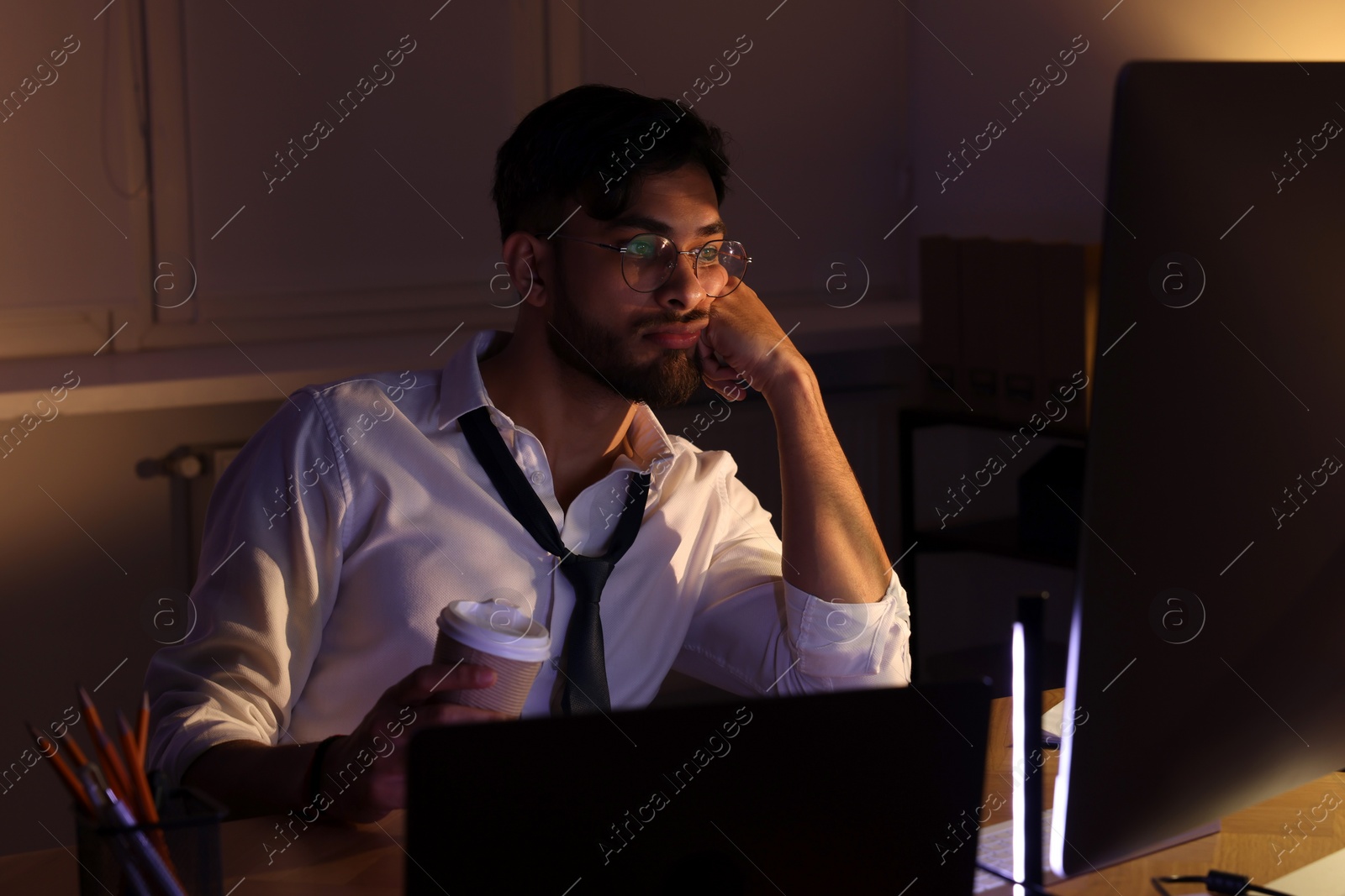 Photo of Tired man with coffee working late in office