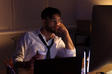 Photo of Tired man with coffee working late in office