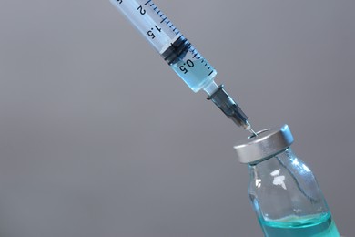 Photo of Filling syringe with medicine from vial on grey background, closeup. Space for text