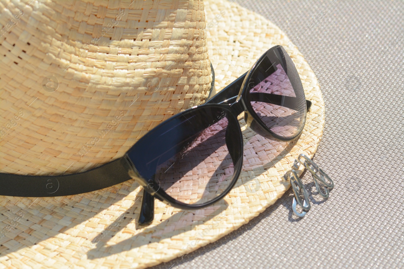 Photo of Stylish hat, sunglasses and jewelry on grey surface, closeup