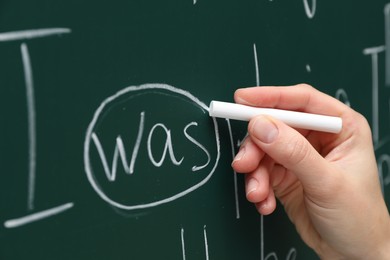 Photo of English teacher writing with chalk on green chalkboard, closeup