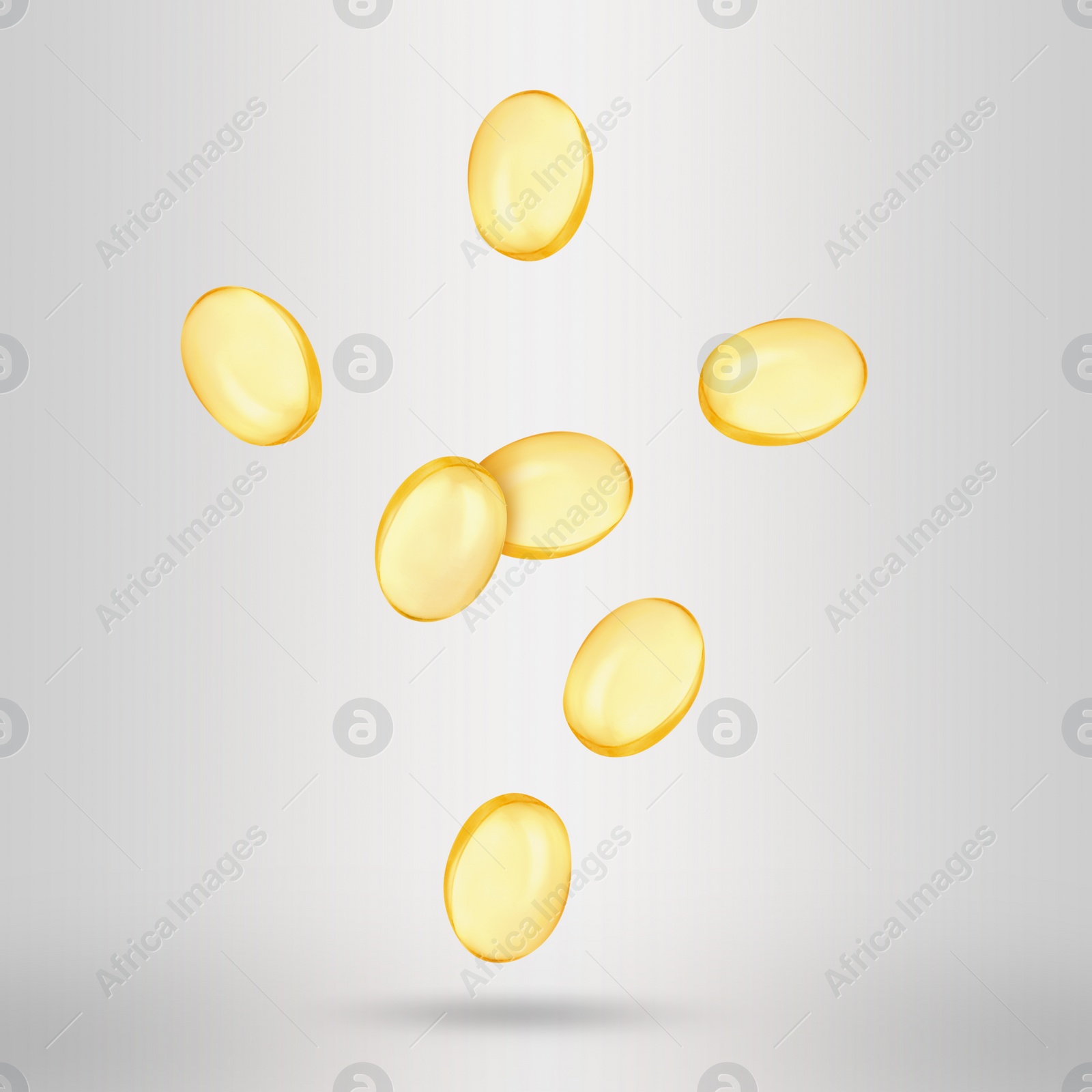 Image of Vitamin. Softgel capsules falling on light grey background